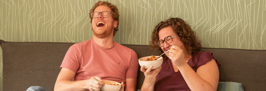Man en vrouw in bed aan het eten en lachen